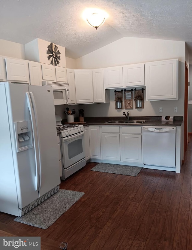 kitchen featuring white appliances, white cabinets, dark countertops, dark wood-style flooring, and a sink