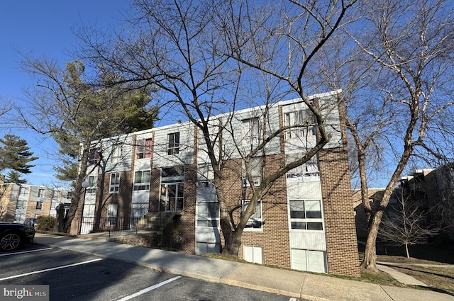 multi unit property with brick siding and uncovered parking