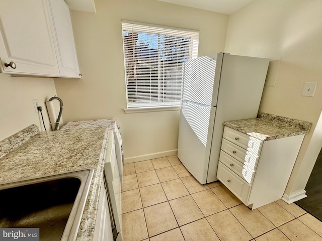 kitchen with light countertops, light tile patterned floors, freestanding refrigerator, and a sink