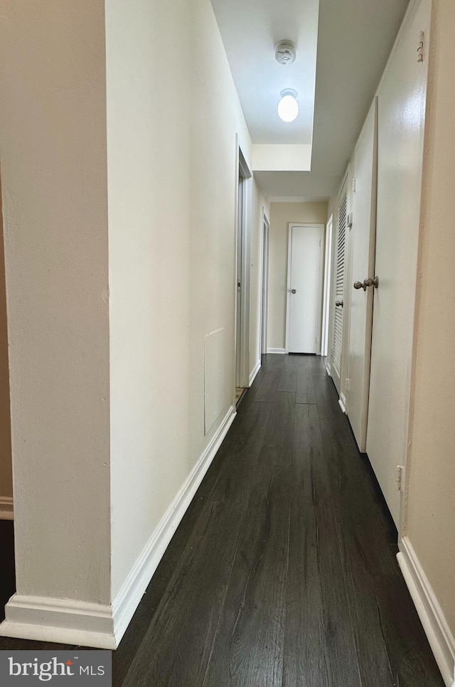 corridor featuring dark wood-style floors and baseboards