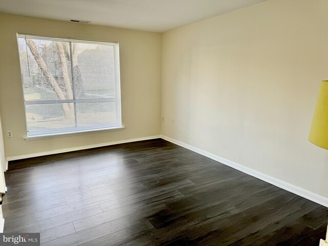 spare room featuring dark wood finished floors, baseboards, and visible vents