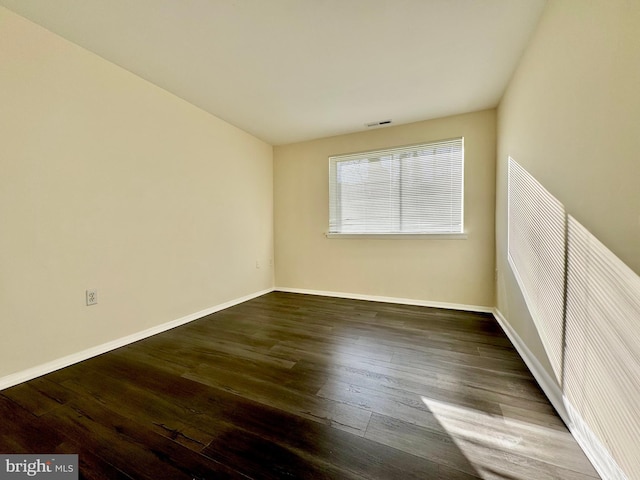 spare room with visible vents, baseboards, and wood finished floors