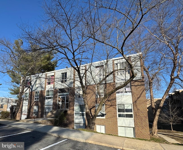 multi unit property featuring brick siding and uncovered parking