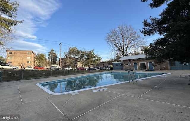 pool with a patio area and fence