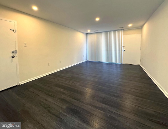 empty room with dark wood-type flooring, recessed lighting, and baseboards