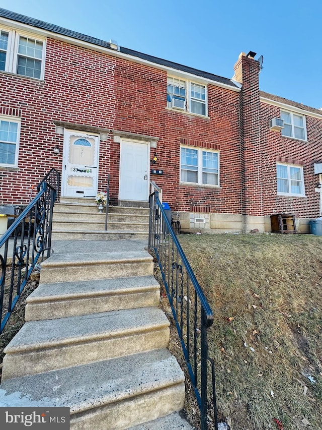 view of front of property with entry steps, a chimney, and brick siding