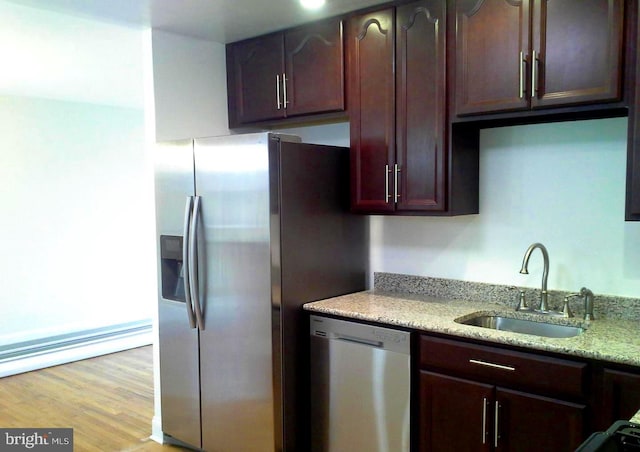 kitchen with light stone counters, sink, light hardwood / wood-style floors, and appliances with stainless steel finishes