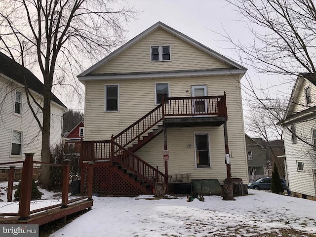 snow covered rear of property featuring a balcony