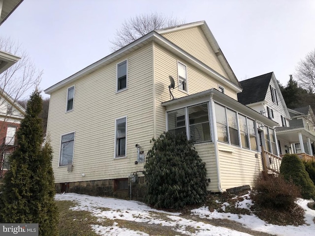 view of snow covered exterior featuring a sunroom