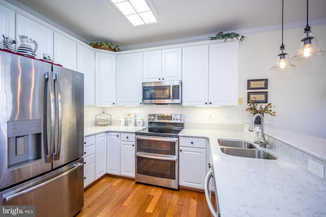 kitchen with sink, decorative light fixtures, light hardwood / wood-style flooring, appliances with stainless steel finishes, and white cabinets