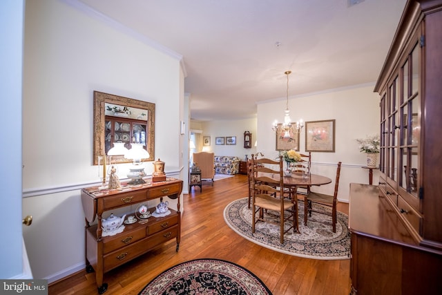 dining area featuring crown molding, a notable chandelier, and hardwood / wood-style flooring