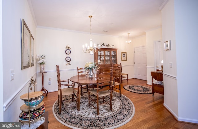 dining space featuring hardwood / wood-style flooring, crown molding, and a chandelier