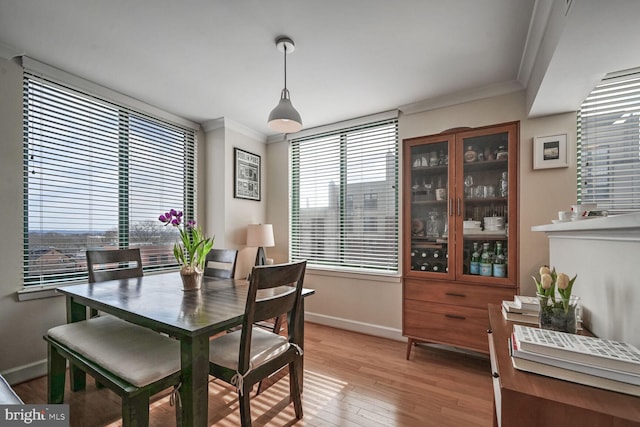 dining area featuring crown molding, plenty of natural light, and light wood-type flooring