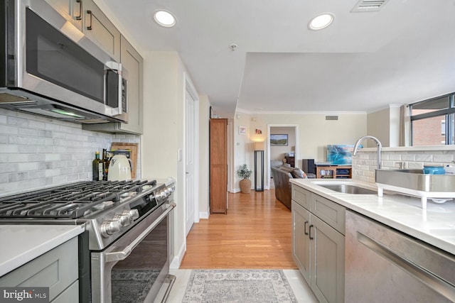 kitchen with appliances with stainless steel finishes, tasteful backsplash, sink, gray cabinetry, and light hardwood / wood-style flooring