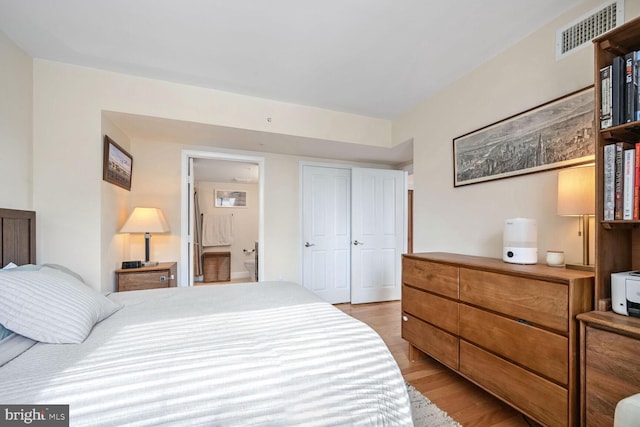 bedroom featuring ensuite bath, a closet, and light wood-type flooring