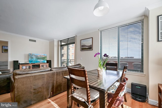 dining area featuring ornamental molding and light hardwood / wood-style floors