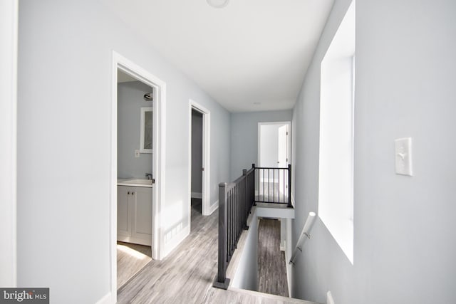 hall with sink and light wood-type flooring