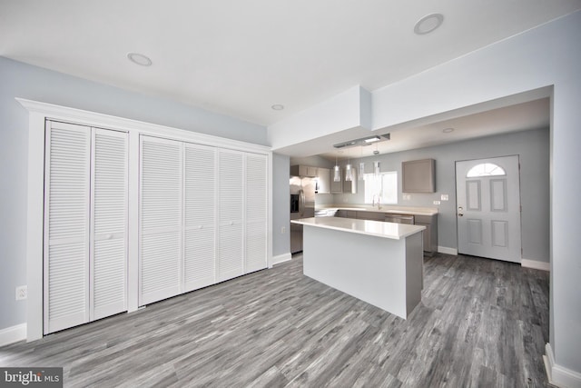 kitchen featuring a kitchen island, appliances with stainless steel finishes, pendant lighting, and light wood-type flooring