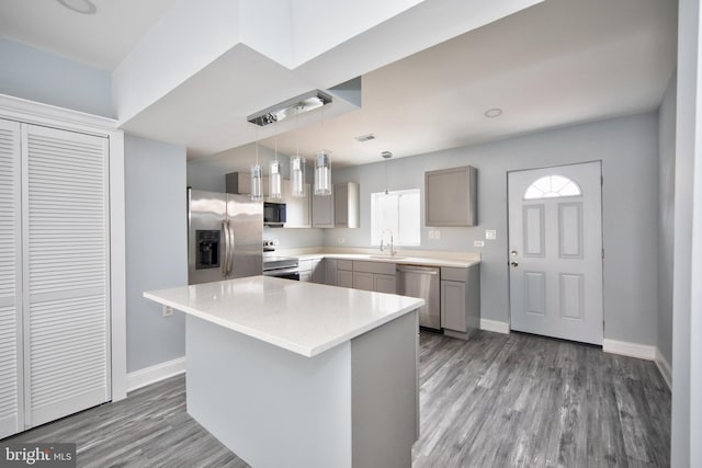 kitchen featuring sink, gray cabinets, hanging light fixtures, stainless steel appliances, and a center island