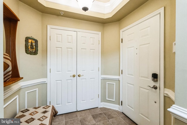 foyer entrance featuring crown molding, wainscoting, and a decorative wall