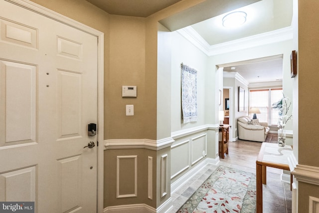 foyer with a wainscoted wall, a decorative wall, and crown molding