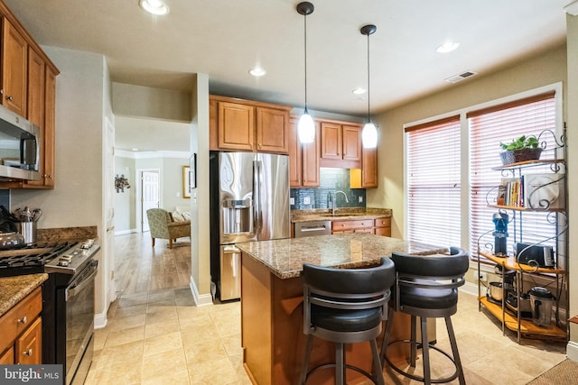 kitchen with stone counters, stainless steel appliances, a sink, visible vents, and brown cabinetry