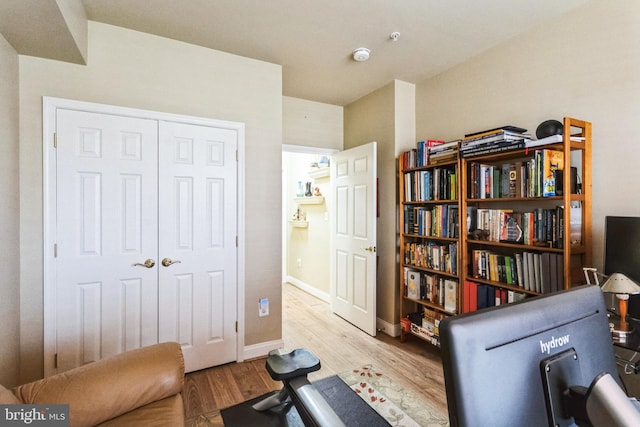 exercise area with light wood-style flooring and baseboards