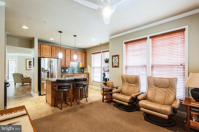 kitchen with a sink, a kitchen breakfast bar, brown cabinets, stainless steel fridge with ice dispenser, and decorative light fixtures