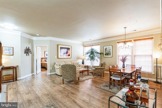 living area with baseboards, visible vents, ornamental molding, light wood-style floors, and a chandelier