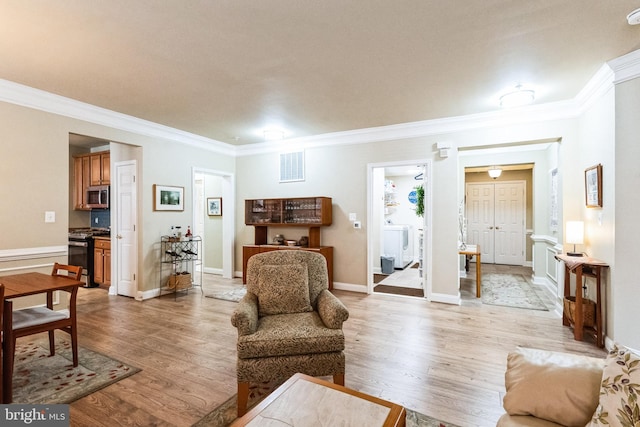 living room with light wood-type flooring, visible vents, washer / clothes dryer, and ornamental molding