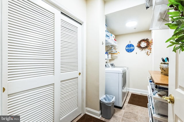 laundry room featuring washing machine and dryer, laundry area, baseboards, and light tile patterned floors