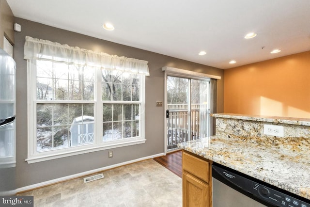 kitchen featuring dishwasher, light stone countertops, and a wealth of natural light