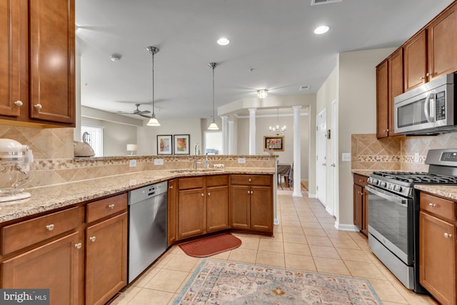 kitchen featuring stainless steel appliances, light stone countertops, decorative light fixtures, light tile patterned flooring, and sink