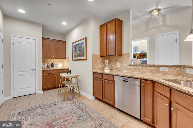 kitchen with stainless steel dishwasher, light tile patterned flooring, light stone countertops, and decorative light fixtures