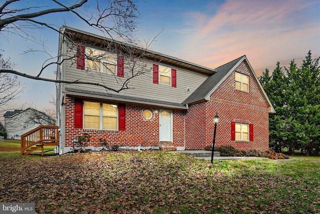 traditional-style home with brick siding and a front lawn