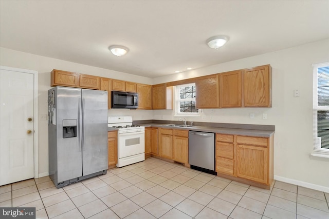 kitchen with light tile patterned floors, stainless steel appliances, a sink, baseboards, and light countertops