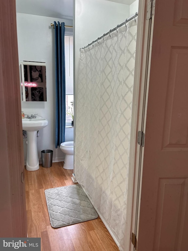 bathroom featuring hardwood / wood-style flooring, sink, curtained shower, and toilet