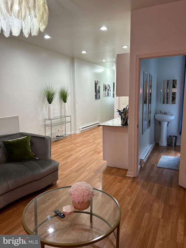 living room with baseboard heating, wood-type flooring, and sink