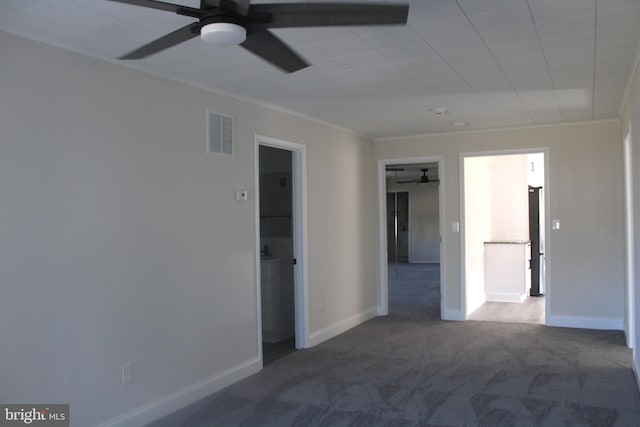 carpeted empty room featuring visible vents, crown molding, and baseboards