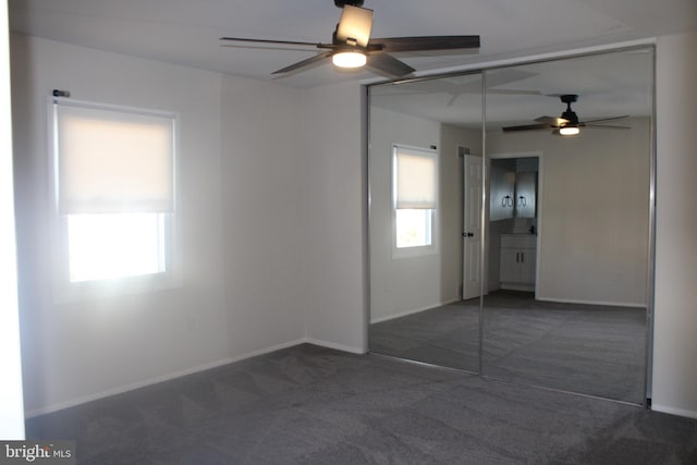 carpeted spare room featuring ceiling fan and baseboards