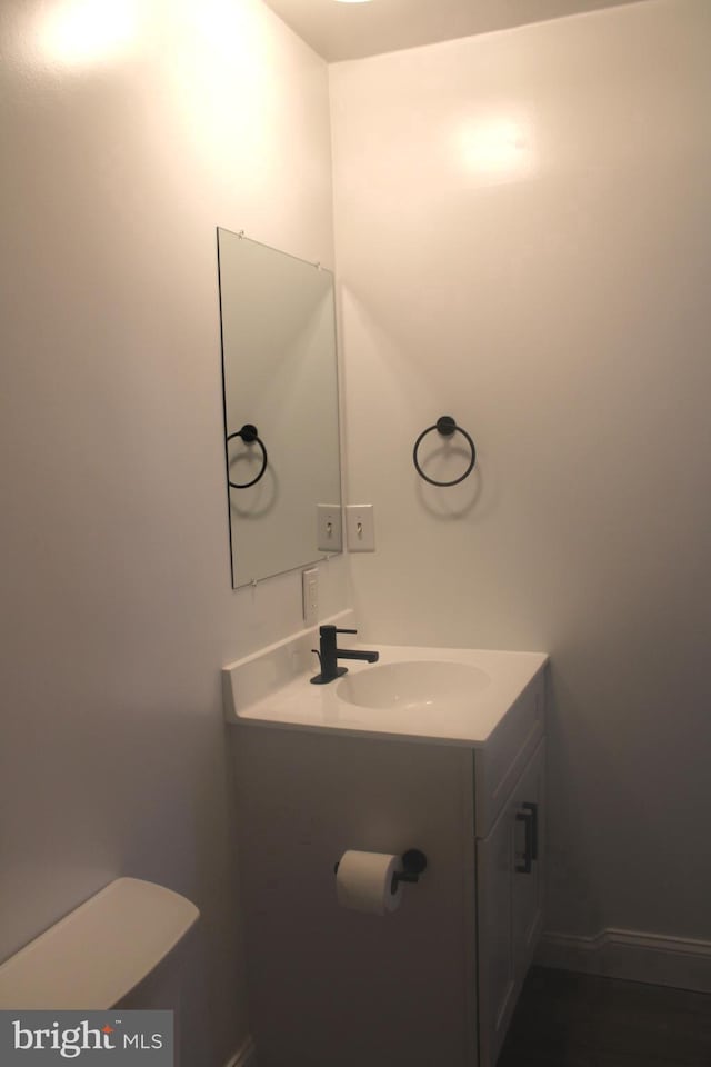 bathroom featuring toilet, baseboards, and vanity