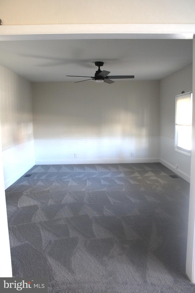 unfurnished room featuring dark carpet, baseboards, and ceiling fan