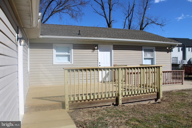 exterior space with a wooden deck and roof with shingles