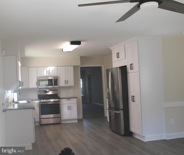 kitchen featuring dark wood finished floors, white cabinets, decorative backsplash, appliances with stainless steel finishes, and a sink