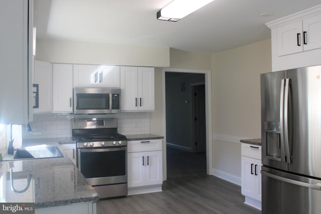 kitchen with stainless steel appliances, tasteful backsplash, stone countertops, dark wood-type flooring, and white cabinets