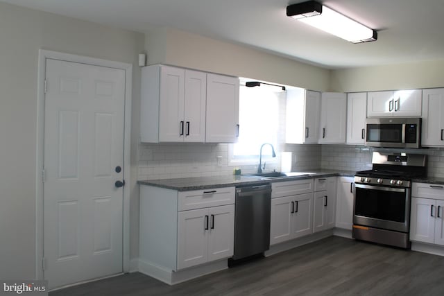 kitchen with stainless steel appliances, dark wood-style flooring, a sink, and backsplash