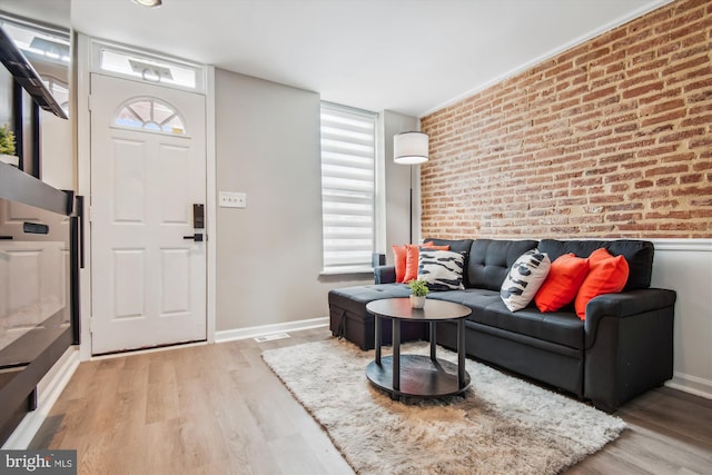 foyer entrance with light hardwood / wood-style flooring and brick wall