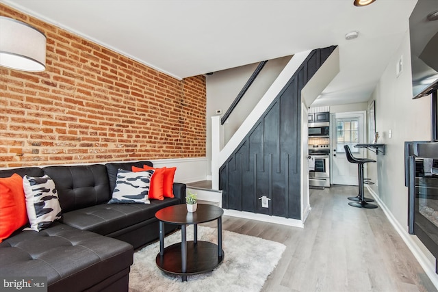 living room featuring brick wall and light hardwood / wood-style floors