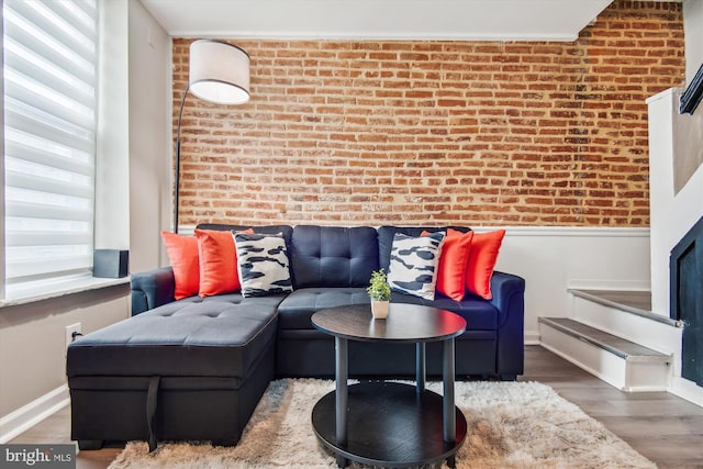 living room featuring wood-type flooring and brick wall