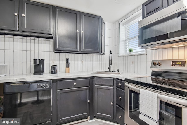 kitchen with tasteful backsplash, sink, light stone countertops, and appliances with stainless steel finishes